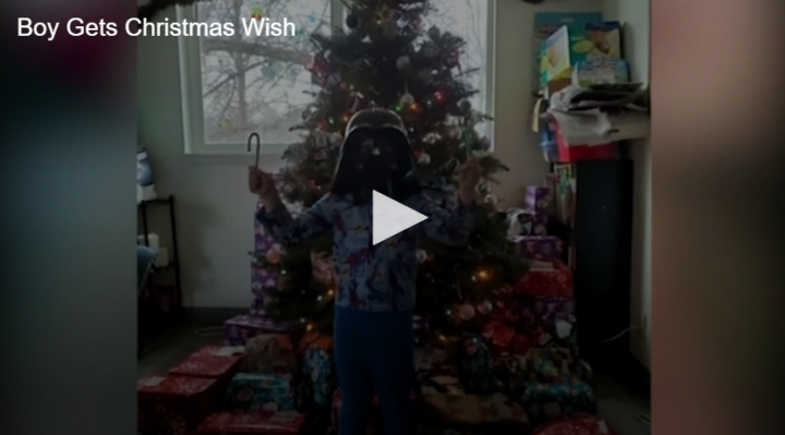 Christmas tree with a boy in a vader mask standing in front of it