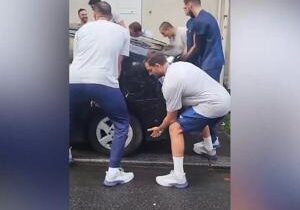 Olympic water polo team gets off bus to lift parked cars in way